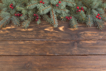 Christmas composition of fir branches and berries of viburnum on a wooden background . Top view with copy space.