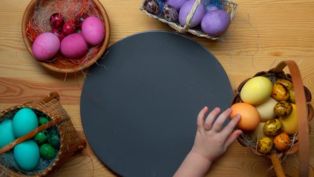 Child's hand lays colored festive easter eggs in different baskets