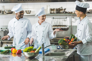 smiling multicultural chefs talking at restaurant kitchen