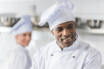 smiling multicultural chefs at restaurant kitchen