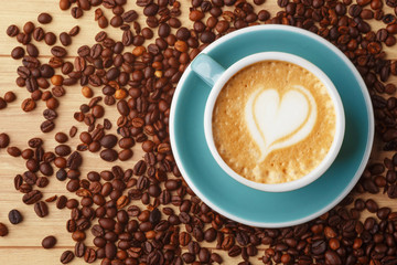 A cup of fragrant coffee in foam on a wooden table. Latte art. Coffee beans.