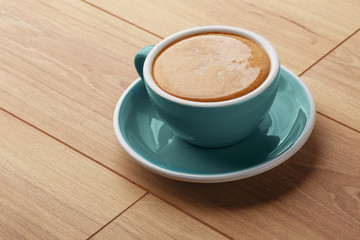 A cup of fragrant coffee in foam on a wooden table.