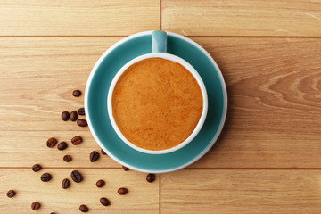 A cup of fragrant coffee in foam on a wooden table.