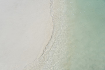 Fototapeta na wymiar closed up clear and blue wave of the sea on white beautiful island beach
