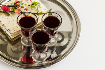 Passover,The Feast of Unleavened Bread with stylish,three wine glass and matzah breads on the shinny metal tray,at the white background.Close up taken,isolated.