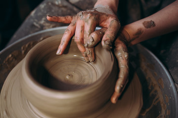 Female potter making clay pottery on a spin wheel.