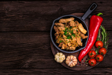 Fried pork in frying pan and vegetables