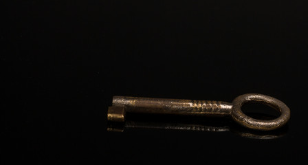 Old iron key isolated on black reflective surface