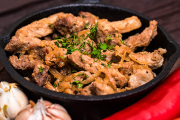 Fried pork in frying pan and vegetables