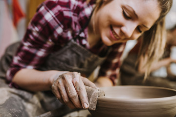 Female potter making clay pottery on a spin wheel.