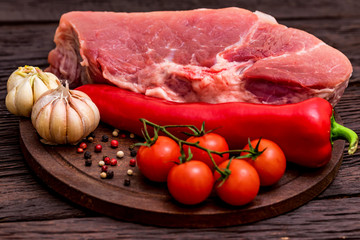 Raw pork steak with pepper, herbs and tomatoes