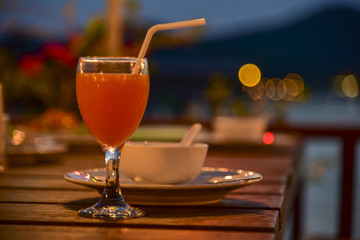 A glass of fruit juice put on dinner table with blow of soup in the restaurant.