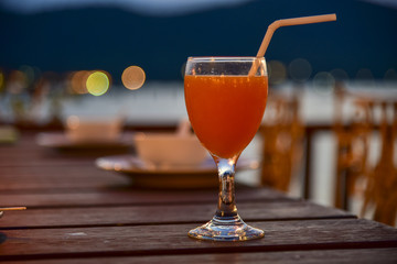 A glass of fruit juice put on dinner table with blow of soup in the restaurant.