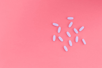 White vaginal pills on a bright pastel pink background and a place for the text. Flat lay