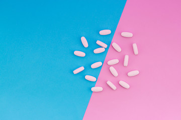 Vitamins lie on a colored background. Tablets on the blue and pink pastel background. Place for text. Top view
