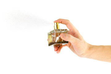Fototapeta premium The hand holding the Cologne. Sprays perfume. Isolated on a white background. Close up