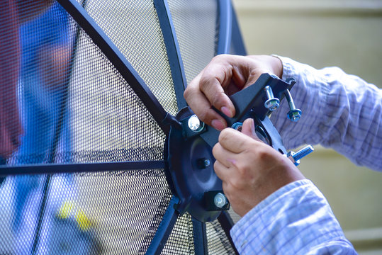 Technician installing Satellite dish system for television signal.
