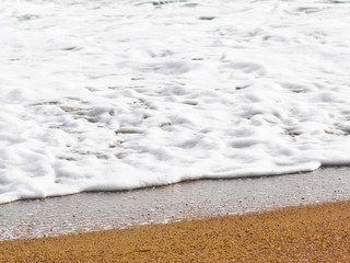 Sea white foam on a yellow sandy beach