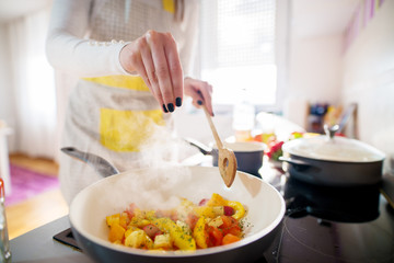 Close up of a young woman hands putting just enough space on her cooking mixture in a pan on the oven.