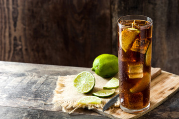 Cuba libre. Cocktail with rum, lime and ice on wooden table. Copyspace