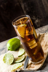 Cuba libre. Cocktail with rum, lime and ice on wooden table. 