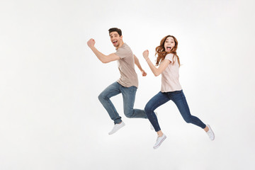 Fototapeta na wymiar Full-length photo of happy couple man and woman in casual t-shirt running and smiling on camera with joyful look, isolated over white background
