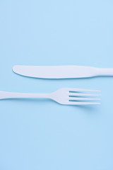 Clean new white knife and fork creative flat lay on trendy soft blue paper background