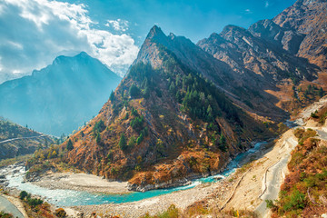Himalayan mountain landscape with a sharp conical wooded mountain and curving river and road in the foreground, the Himalayas, Uttarakhand near Badrinath, India