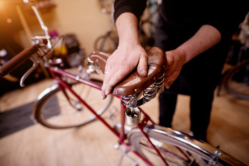 Close up view of man's hands pressing bicycle seat to check its suspension.