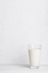 Full glass of milk on white wooden table background vertical with copy space