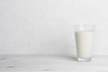 Glass of milk on white wooden table and white background with side copy space - obrazy, fototapety, plakaty