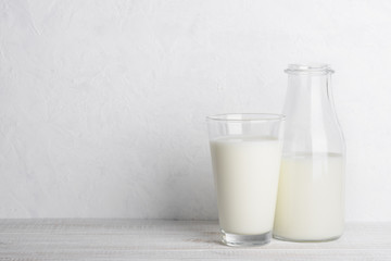 Bottle and glass of milk on white wooden table still life with copy space