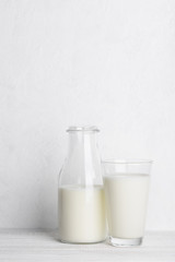 Bottle ang glass of milk on white wooden table background vertical with copy space