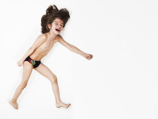 Young Caucasian boy running action on light background