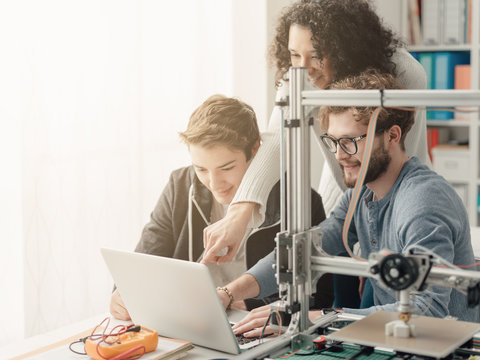 Group of students using a 3D printer and a laptop
