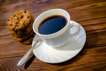 A cup of hot coffee stands on a wooden table 