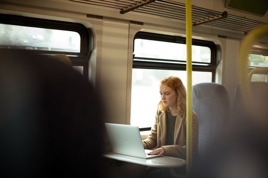 Young woman using a laptop while traveling in train