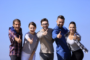 smiling group of young people showing thumb up.