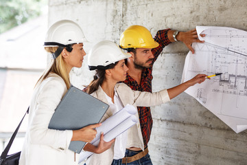 Team of inspectors and architects discuss about blueprints on construction site.