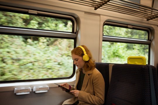 Young woman listing to music while using tablet