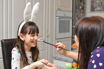 Mom and girl smiling and play with Easter eggs and paint. Mother and daughter painting Easter eggs. Happy family