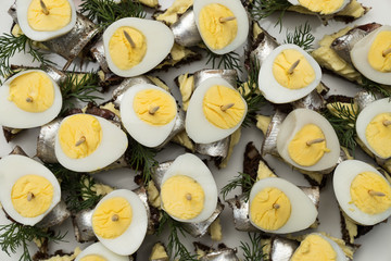 Mini sandwich with salt sprat and sliced boiled quail egg on the slice of bread. Canned fish is Estonian national food.   Concept of food and organic farm products.