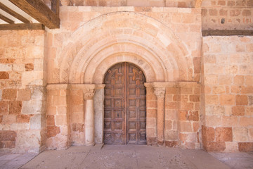 Exterior facade with wooden door, decorated archs and columns, in church of San MIguel (Saint Michael), from twelfth century, in Ayllon village, Segovia, Spain, Europe
