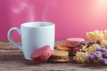 Different types color of macaroons with Cup of hot tea on Old grunge wooden background
