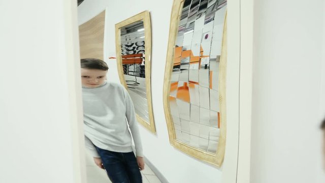 Boy playing with distorted mirror. Museum of entertaining sciences