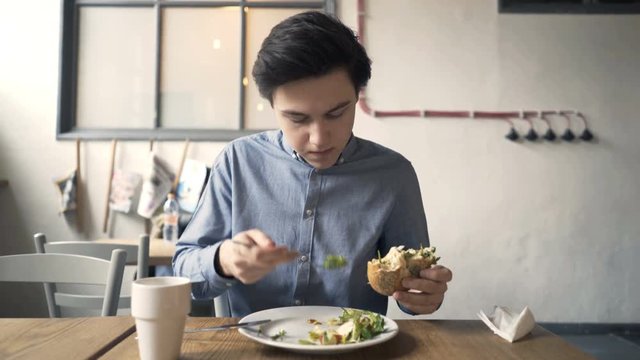 Young teenager eating sandwich in cafe
