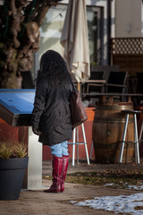 woman in red boots studies menu in fron of a restaurant in winter