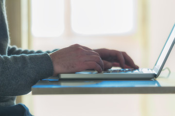 Man's hands working on a laptop keyboard.