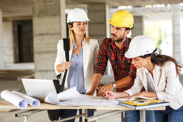 Two female inspectors and architects discuss with head engineer about construction project.