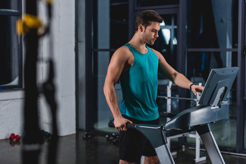 Obraz na płótnie Canvas handsome sportsman training on treadmill in gym
